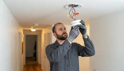 Electrician installing an interconnected smoke detector on a ceiling in a Santa Rosa, CA home
